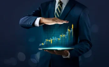 A businessman in a suit holds a tablet displaying a glowing upward stock graph, symbolizing financial growth and investment success.