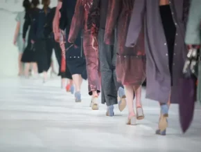 A group of women confidently walking down a runway, showcasing stylish outfits and high heels during a fashion show.