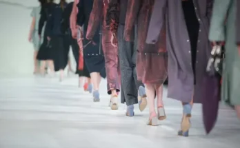 A group of women confidently walking down a runway, showcasing stylish outfits and high heels during a fashion show.