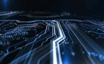 Close-up view of an illuminated circuit board with intricate blue and white lines representing electronic pathways on a dark background.