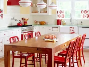 A kitchen featuring a table and chairs, with cabinetry on the walls, a countertop, and various kitchen appliances. The floor is visible along with home décor elements.