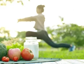 A woman exercises outdoors with fresh vegetables and a jar of milk on a table, highlighting a healthy lifestyle.