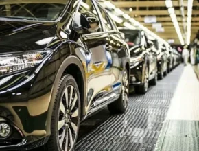 A row of sleek black cars on an assembly line, showcasing the manufacturing process in a modern factory setting.