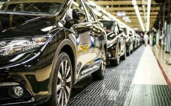 A row of sleek black cars on an assembly line, showcasing the manufacturing process in a modern factory setting.
