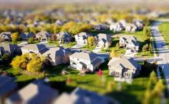 Aerial view of a suburban neighborhood with neatly arranged houses, green lawns, and trees in autumn colors.