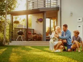 A family enjoys quality time in their backyard, with a sunny atmosphere, grass, and a modern home in the background.