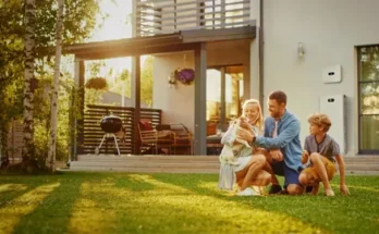 A family enjoys quality time in their backyard, with a sunny atmosphere, grass, and a modern home in the background.