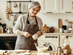 A Lady in a cozy kitchen mixes ingredients in a large bowl, surrounded by baking supplies and a warm, inviting atmosphere.