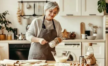 A Lady in a cozy kitchen mixes ingredients in a large bowl, surrounded by baking supplies and a warm, inviting atmosphere.