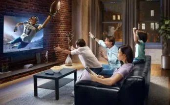 A family cheers excitedly while watching a football game on TV in a cozy living room, with snacks on the coffee table.