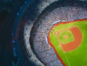 Aerial view of a packed baseball stadium, showcasing the vibrant green field and bustling crowd surrounding the diamond.
