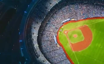 Aerial view of a packed baseball stadium, showcasing the vibrant green field and bustling crowd surrounding the diamond.