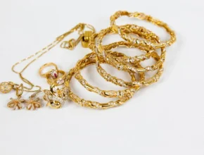 A collection of elegant gold jewelry including rings, bangles, and necklaces, adorned with intricate designs and sparkling stones.