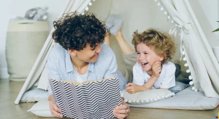 A cozy scene of a parent reading a book inside a tent-like structure to a child, surrounded by soft cushions and playful decor.