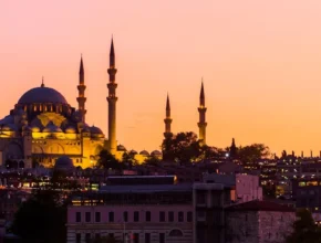 Silhouette of a mosque with multiple minarets against a vibrant sunset sky in Istanbul, Turkey.