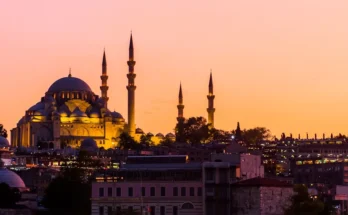 Silhouette of a mosque with multiple minarets against a vibrant sunset sky in Istanbul, Turkey.