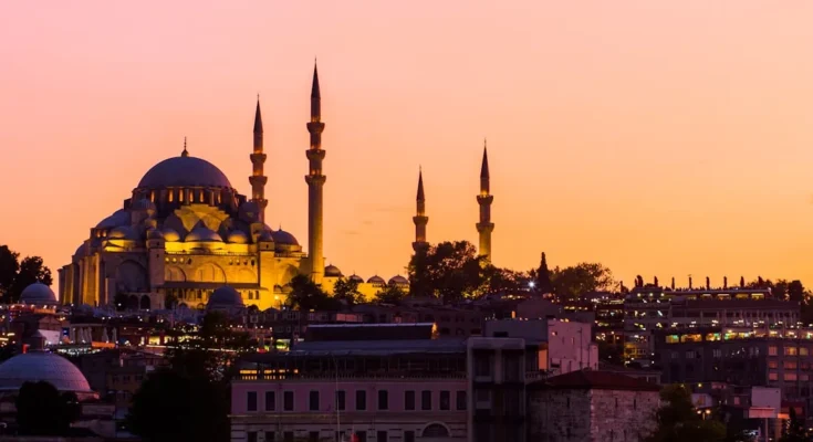 Silhouette of a mosque with multiple minarets against a vibrant sunset sky in Istanbul, Turkey.