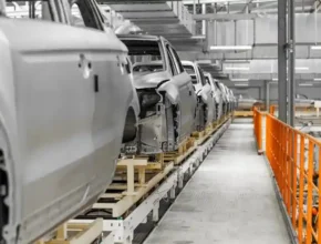 A row of unfinished car bodies on an automated assembly line within a modern factory setting, showcasing an industrial production scene.