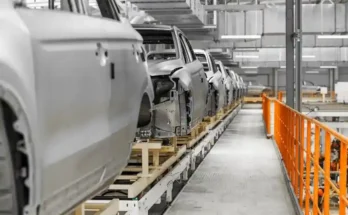 A row of unfinished car bodies on an automated assembly line within a modern factory setting, showcasing an industrial production scene.