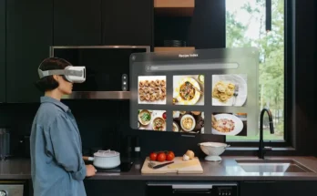 A person wearing a VR headset stands in a modern kitchen, viewing digital recipe images on a virtual screen while preparing food.